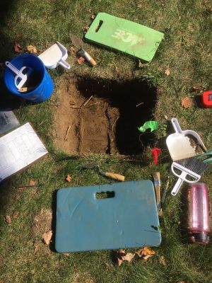 A test pit surrounded by the archaeological tools used at a typical dig site